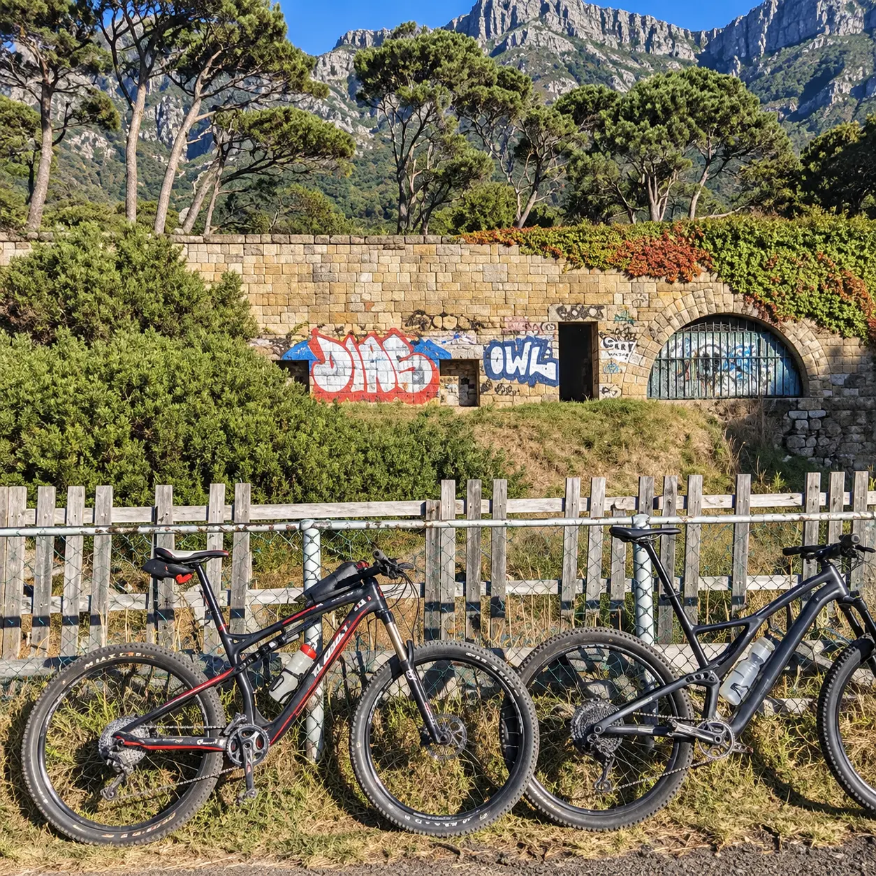 Two mountain bikes beside a trail fence with rugged mountain scenery in Cape Town.